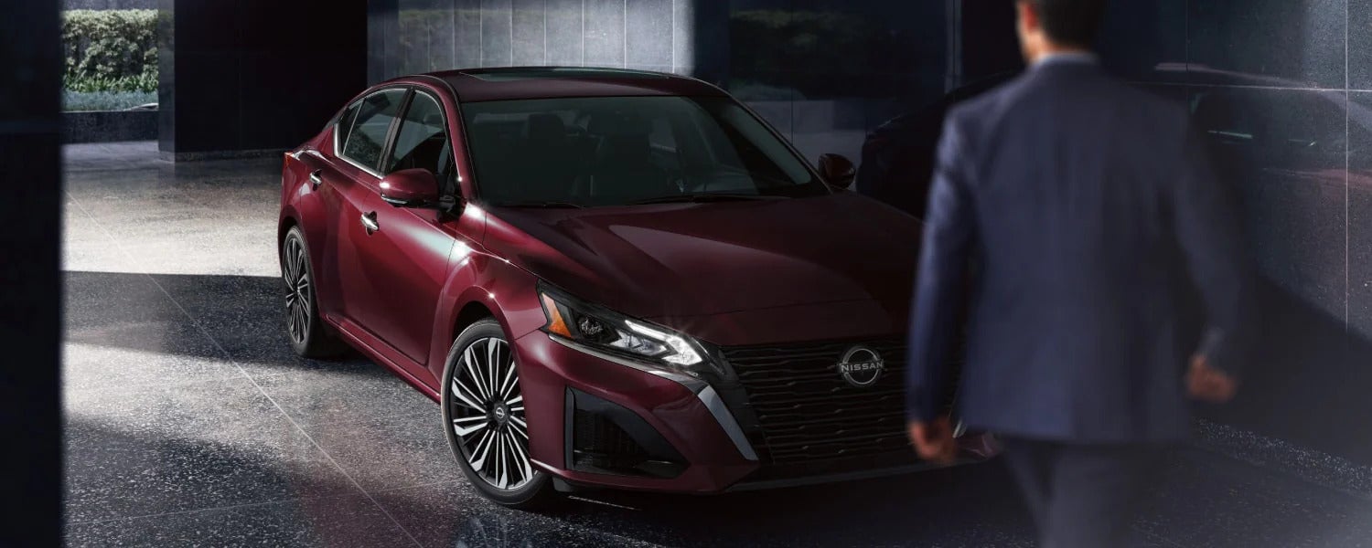 Man standing next to a red Nissan Altima
