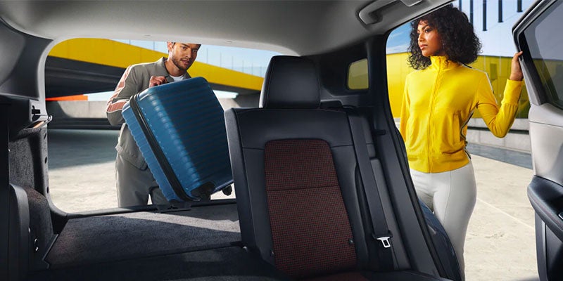 Man loading a suitcase into the back of a Nissan Kicks